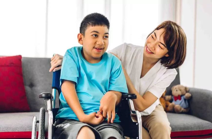 Henkilökohtainen avustaja katsoo pyörätuolissa istuvaa lasta Espoossa